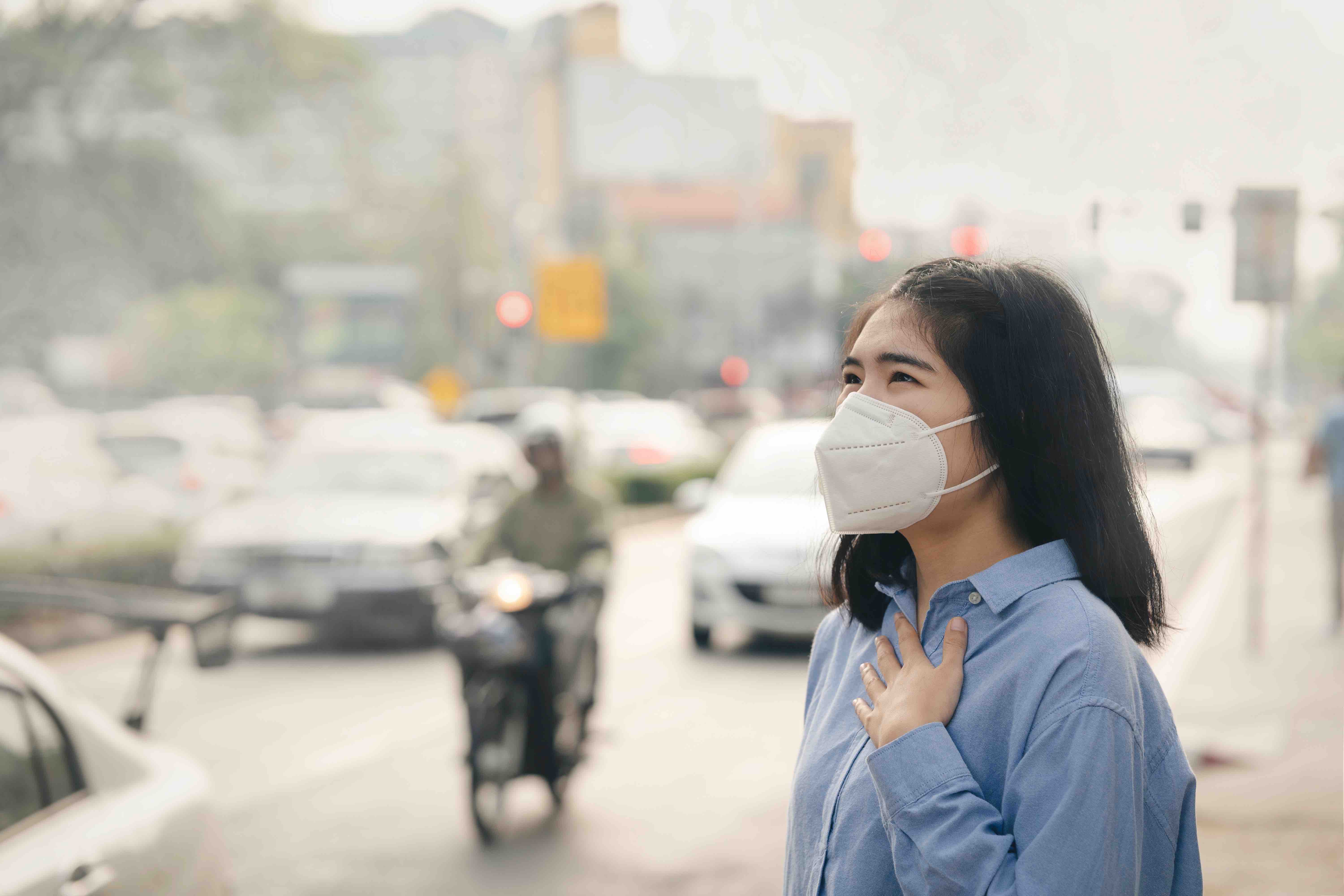women with face mask in smoggy urban setting